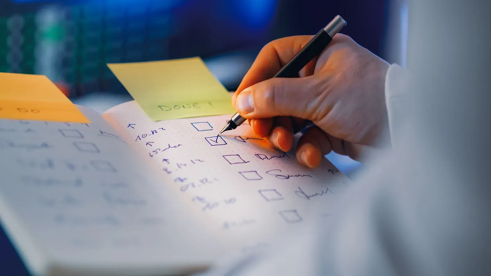 Eine Hand hakt Punkte auf einer handgeschriebenen Checkliste im Notizbuch ab